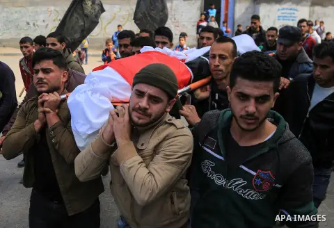 Palestinian mourners carry the body of a member of Palestinian Al-Quds Brigades militant Ibrahim Farhat, 29, who was died yesterday in an explosion during his funeral in Beit lahia in the northern Gaza Strip on March 11,...