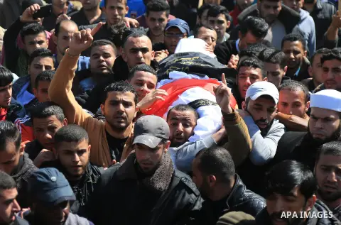 Palestinian mourners carry the body of a member of Palestinian Al-Quds Brigades militant Ibrahim Farhat, 29, who was died yesterday in an explosion during his funeral in Beit lahia in the northern Gaza Strip on March 11,...