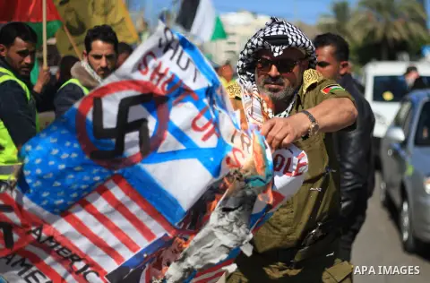 Palestinians burn an Israeli, British and U.S. flags during a protest to show solidarity with Palestinian prisoners held in Israeli jails, in front of Red cross office in Gaza city on March 12, 2018. Photo by Mahmoud Ajo...