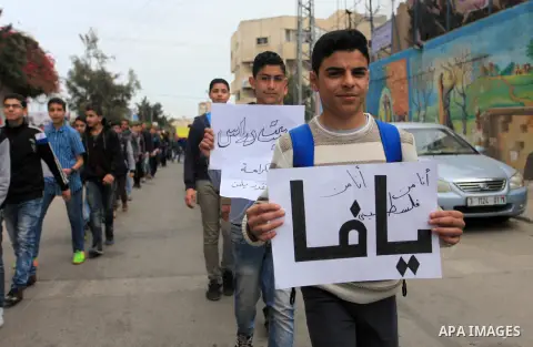 Palestinians from a human chain hold banners during a protest against a U.S. decision to cut aid, in Gaza City on March 15, 2018. Photo by Mahmoud Ajour