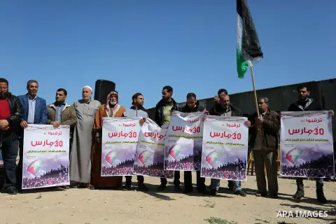 Palestinians hold placards and the national flags during a rally against "Deal of the Century" and to announce the launch of the great return march near the border with Israel in east of Gaza city on March 17, 2018. Phot...