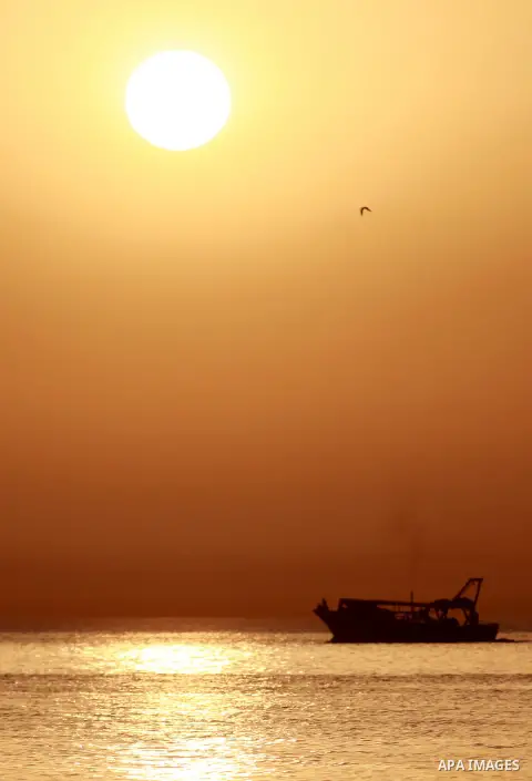 Palestinians ride their boat in the sea of Gaza city during sunset on March 19, 2018. Photo by Yasser Qudih