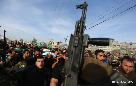 Members of Hamas' armed wing al-Qassam Brigades walk guard carrying a Kalashnikov assault rifle during the funeral of Ziad al-Howajri, one of the members of Hamas' security forces, in al-Nusairat refugee camp in the cent...