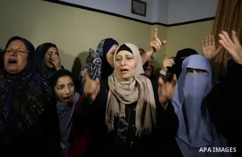 Relatives of Palestinian Ziyad Al-hawajri, react as mourners carry his body out of the family house during his funeral in Nuseirat, central Gaza Strip, Thursday, March 22, 2018. Al-hawajri, is one of the two members of H...