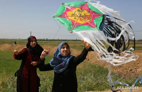A Palestinian woman flys kite during a protest in a tent city along Israel border with Gaza, demanding to return to their home land, east of Gaza City, March 29, 2018. Photo by Ashraf Amra