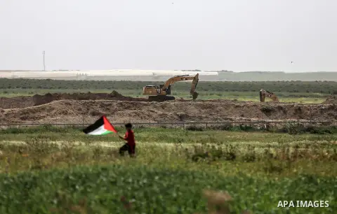 A Palestinian protester waves a Palestine flag, near Israel border east of Gaza City, March 29, 2018. Photo by Dawoud Abo Alkas
