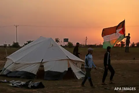 Paleatinians gather next to tents pitched by Palestinians on the Gaza border with Israel, in the southern Gaza Strip, on March 29, 2018, ahead of a six-week protest camp. The exceptional protest is dubbed "The Great Marc...