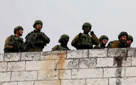 Israeli security forces stand guard on a house roof during clashes with Palestinian protesters at a demonstrarion marking Land Day, in Hebron, in the occupied West Bank March 30, 2018. Photo by Wisam Hashlamoun
