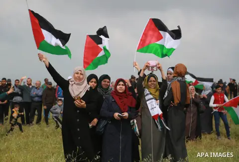 Palestinian women wave Palestinian flags during a tent city protest along the Israel border with Gaza, demanding the right to return to their homeland, east of Gaza City March 30, 2018. Photo by Mohammed Dahman