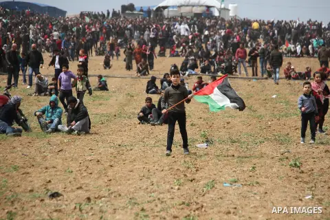 A Palestinian boy waves a Palestinian flag during a tent city protest along the Israel border with Gaza, demanding the right to return to their homeland, east of Jabalia, in the northern of Gaza Strip on March 30, 2018....