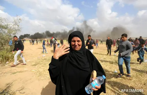 A Palestinian woman reacts from tear gas fired by Israeli security forces during clashes, in a tent city protest along the Israel border with Gaza, demanding the right to return to their homeland, in Khan Younis in the s...