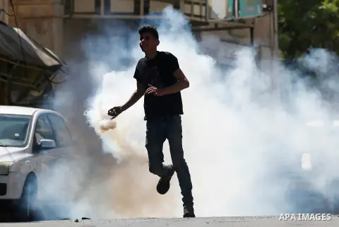 A Palestinian protester throws back a tear gas canister fired by Israeli security forces during clashes on March 31, 2018 in occupied West Bank city of Hebron as a general strike is called for by local leaders in solidar...