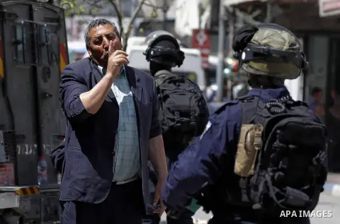 A Palestinian man argues with Israeli security forces as they protect Jewish settlers during visit the tomb of Othniel Ben Kenaz in the West Bank city of Hebron on April 2, 2018. Photo by Wisam Hashlamoun