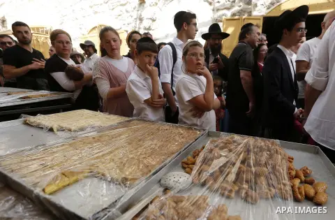 Jewish settlers gather as a Palestinian vendor makes traditional sweets in Hebron, in the occupied West Bank April 3, 2018. Photo by Wisam Hashlamoun