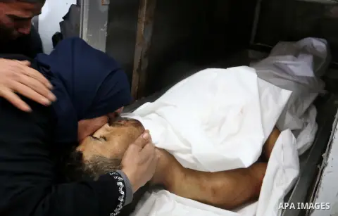 Relatives of Palestinian Ahmed Arafa, 25, who was killed by Israeli security forces during clashes along Israel border with Gaza, mourn over his body in morgue at a hospital in the central Gaza Strip April 3, 2018. Photo...
