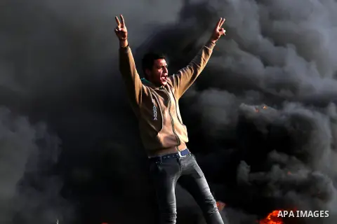 A Palestinian protester flashes victory sign during clashes with Israeli security forces in a tent city protest along the Israel border with Gaza, demanding the right to return to their homeland, in east of Gaza city on...