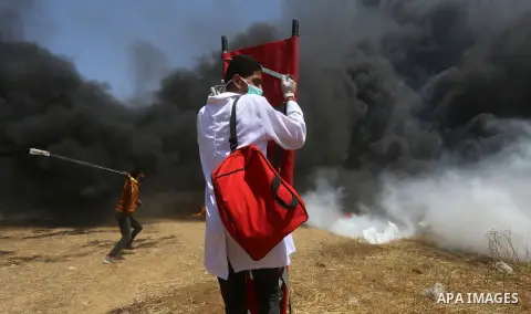 Palestinian medicals uses stretcher to cover themselve from a tear gas canisters fired by Israeli security forces during clashes at the Israel-Gaza border in a tent city protest demanding the right to return to their hom...
