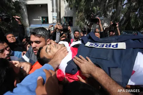 Mourners and journalists carry the body of Palestinian journalist Yasser Murtaja, 30, who died from his injuries after he was shot by Israeli security forces during clashes at the Israel-Gaza border on Friday, during his...
