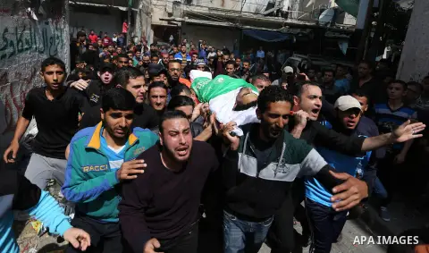 Mourners carry the body of Palestinian Islam Herzallah, 28, who was killed during clashes with Israeli security forces at the Israel-Gaza border during his funeral in Gaza City on April 14, 2018. Photo by Ashraf Amra