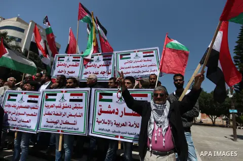 Palestinian protesters hold banners during a protest against U.S. air strikes in Damascus, in Gaza city April 15, 2018. Photo by Mahmoud Ajour