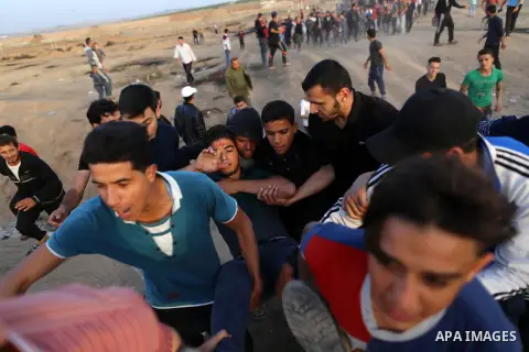 Palestinians evacuate an injured protester during clashes with Israeli security forces near the border with Israel, east of Gaza City, April 18, 2018. Photo by Yasser Qudih