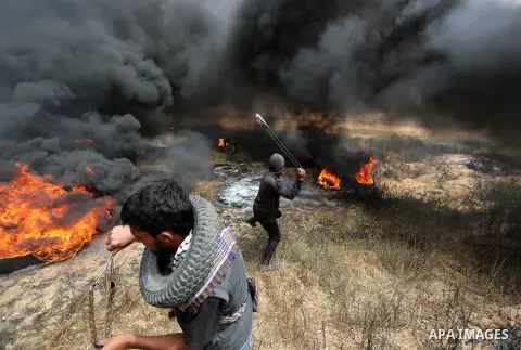 Palestinian protestes use a slingshot to hurl stones during clashes with Israeli security forces at tents protest at the Israel-Gaza border where Palestinians demand the right to return to their homeland, in Khan Younis...