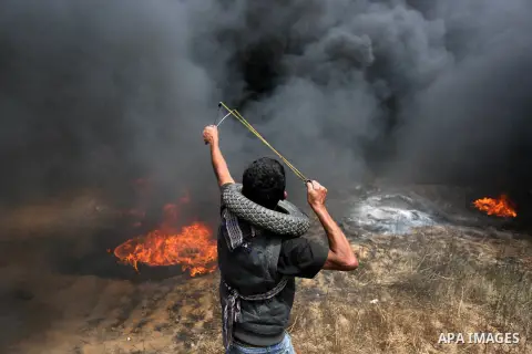 A Palestinian proteste uses a slingshot to hurl stones during clashes with Israeli security forces at tents protest at the Israel-Gaza border where Palestinians demand the right to return to their homeland, in Khan Youni...