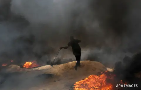 A Palestinian proteste uses a slingshot to hurl stones during clashes with Israeli security forces at tents protest at the Israel-Gaza border where Palestinians demand the right to return to their homeland, in Khan Youni...