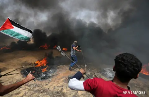 Palestinian protestes use a slingshot to hurl stones during clashes with Israeli security forces at tents protest at the Israel-Gaza border where Palestinians demand the right to return to their homeland, in Khan Younis...