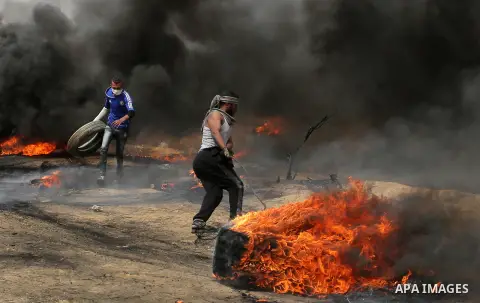 Palestinians burn tires during clashes with Israeli security forces at tents protest at the Israel-Gaza border where Palestinians demand the right to return to their homeland, in Khan Younis in the southern Gaza Strip on...