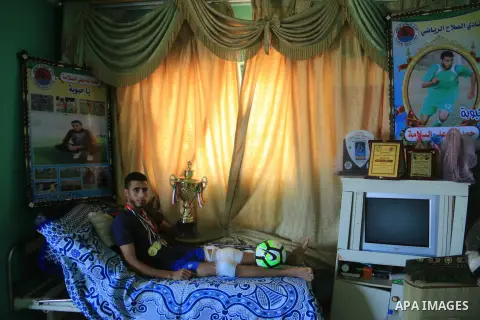 Palestinian football player Mohammed Abu Obaid, 26, who was shot in the leg by Israeli security forces during clashes in tents protest demanding the right to return to their homeland, at the Israel-Gaza border, lies on b...