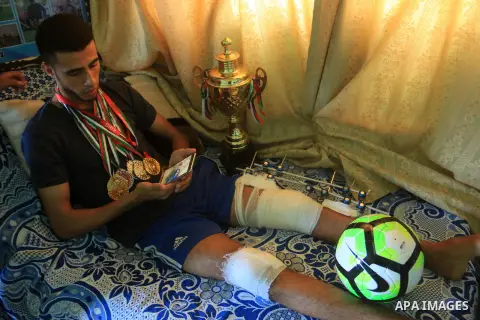 Palestinian football player Mohammed Abu Obaid, 26, who was shot in the leg by Israeli security forces during clashes in tents protest demanding the right to return to their homeland, at the Israel-Gaza border, lies on b...