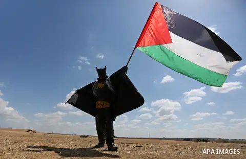 A Palestinian protester dressed as Bat Man waves Palestine flag during a protest demanding the right to return to their homeland, at the Israel-Gaza border in Khan Younis in the southern Gaza Strip, May 9, 2018. Photo by...