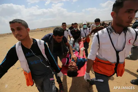 Palestinians carry a protester injured during a protest demanding their rights to return to their homeland, on the occasion of the 70th anniversary of the "Nakba", at Israel-Gaza border, in Khan Younis in the southern Ga...
