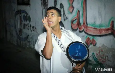 Palestinian man Mahmoud al-Ayidi, 21, a dawn awakener or Al Musaharati in Arabic, who was wounded during clashes with Israeli troops at Israeli-Gaza borders, beats on his drum to wake Muslims for their overnight 'sahur',...