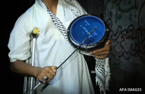 Palestinian man Mahmoud al-Ayidi, 21, a dawn awakener or Al Musaharati in Arabic, who was wounded during clashes with Israeli troops at Israeli-Gaza borders, beats on his drum to wake Muslims for their overnight 'sahur',...