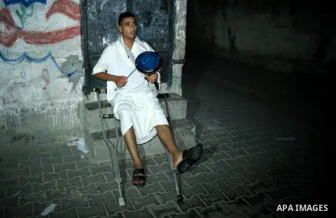 Palestinian man Mahmoud al-Ayidi, 21, a dawn awakener or Al Musaharati in Arabic, who was wounded during clashes with Israeli troops at Israeli-Gaza borders, beats on his drum to wake Muslims for their overnight 'sahur',...