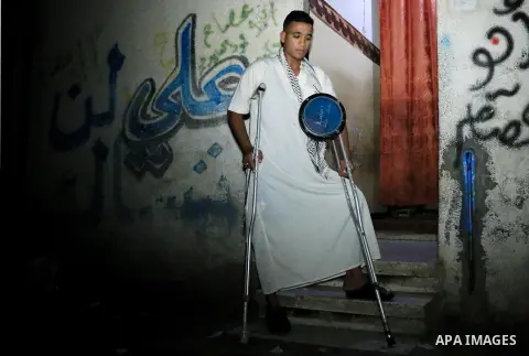 Palestinian man Mahmoud al-Ayidi, 21, a dawn awakener or Al Musaharati in Arabic, who was wounded during clashes with Israeli troops at Israeli-Gaza borders, beats on his drum to wake Muslims for their overnight 'sahur',...