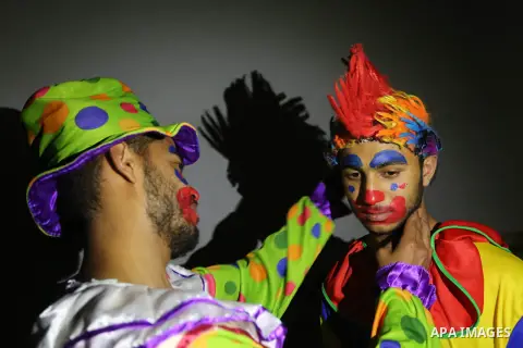 Palestinians dressed as clowns dawn awakener or Al Musaharati in Arabic, beat on their drums to wake Muslims for their overnight 'sahur', last meal, before the day's fast, as they walk through streets, in Dair Al Balah i...
