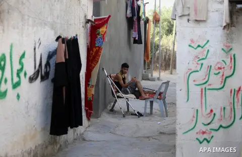 A Palestinian youth Mahmoud Darwish, 17, who was wounded in the leg during clashes with Israeli security forces at the Gaza-Israeli border, sits outside his home, in al-Nusairat refugee camp in the central Gaza Strip on...