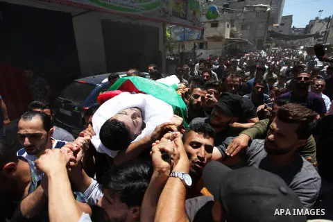 Palestinian mourners carry the body of Mohammed Hamada, 30, who died of his wounds endured during clashes with Israeli troops in a tent city protest where Palestinians demand the right to return to their homeland at the...