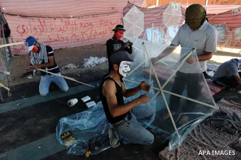 Palestinian protesters prepare kites loaded with flammable material to be flown towards Israel, at the Israel-Gaza border in al-Bureij in the center of Gaza Strip on June 11, 2018. Photo by Ashraf Amra