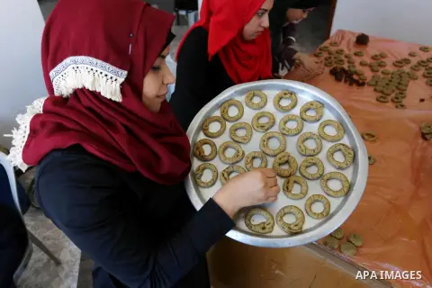 Palestinian women prepare traditional date-filled mini cakes to sell for customers a few days ahead of Eid al-Fitr holiday in Dair Al Balah, in the center of Gaza Strip on June 12, 2018. Eid al-Fitr marks the end of Musl...