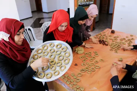Palestinian women prepare traditional date-filled mini cakes to sell for customers a few days ahead of Eid al-Fitr holiday in Dair Al Balah, in the center of Gaza Strip on June 12, 2018. Eid al-Fitr marks the end of Musl...