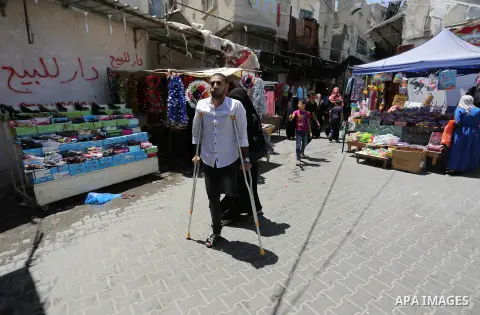 Palestinian disabled Mohammed Al Akhras, 32, who lost his leg by Israeli troops during clashes at Gaza-Israel border uses his crutch to walk at market as he shopping ahead of Eid al-Fitr holiday, in Rafah in the southern...