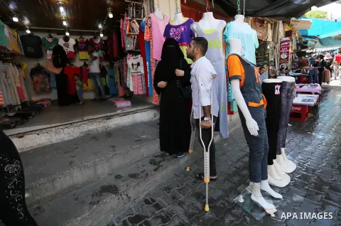 Palestinian disabled Mohammed Al Akhras, 32, who lost his leg by Israeli troops during clashes at Gaza-Israel border uses his crutch to walk at market as he shopping ahead of Eid al-Fitr holiday, in Rafah in the southern...