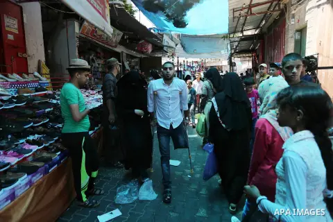 Palestinian disabled Mohammed Al Akhras, 32, who lost his leg by Israeli troops during clashes at Gaza-Israel border uses his crutch to walk at market as he shopping ahead of Eid al-Fitr holiday, in Rafah in the southern...