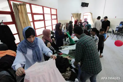 Palestinian volunteers distribute clothes for needy ahead of Eid al-Fitr holiday, in Gaza city on June 14, 2018. Eid al-Fitr marks the end of Muslim's holy fasting month of Ramadan when faithfuls abstain from eating, dri...
