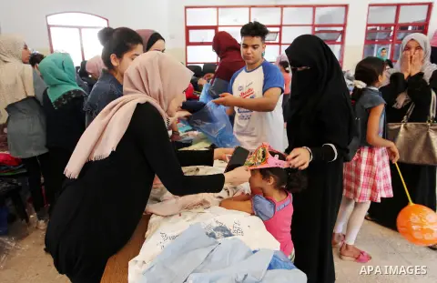 Palestinian volunteers distribute clothes for needy ahead of Eid al-Fitr holiday, in Gaza city on June 14, 2018. Eid al-Fitr marks the end of Muslim's holy fasting month of Ramadan when faithfuls abstain from eating, dri...