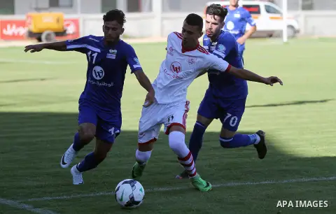 Palestinian players of Hilal al-Quds football club (in blue) compete with Palestinian players of Shabab Khan Younis football club (in white) during the first leg football match of the Palestine Cup final at the Palestine...